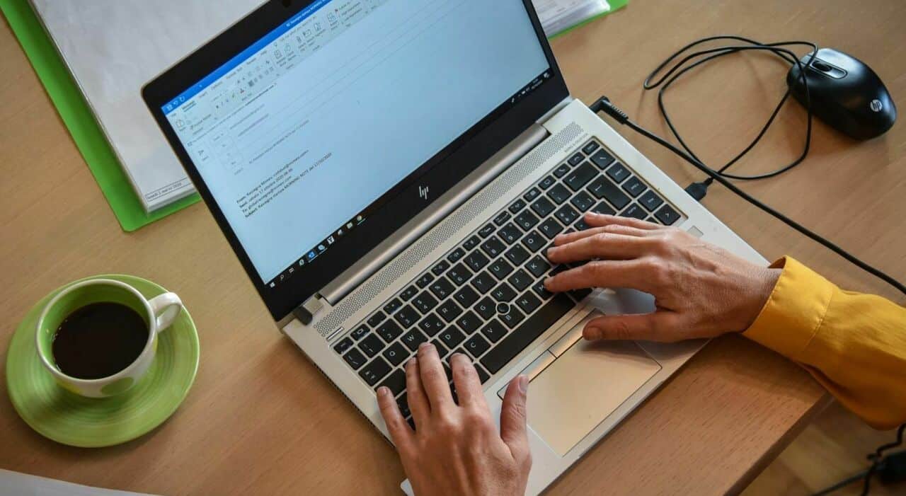 Testo alternativo:Persona che lavora al computer portatile con una tazza di caffè, simbolo di smart working.