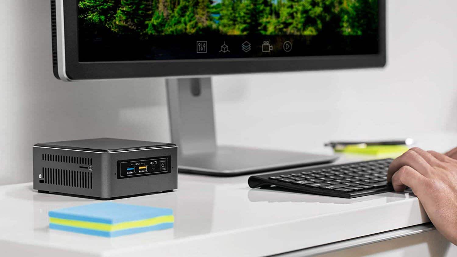 Mini PC compatto su scrivania accanto a monitor e tastiera, prestazioni desktop.