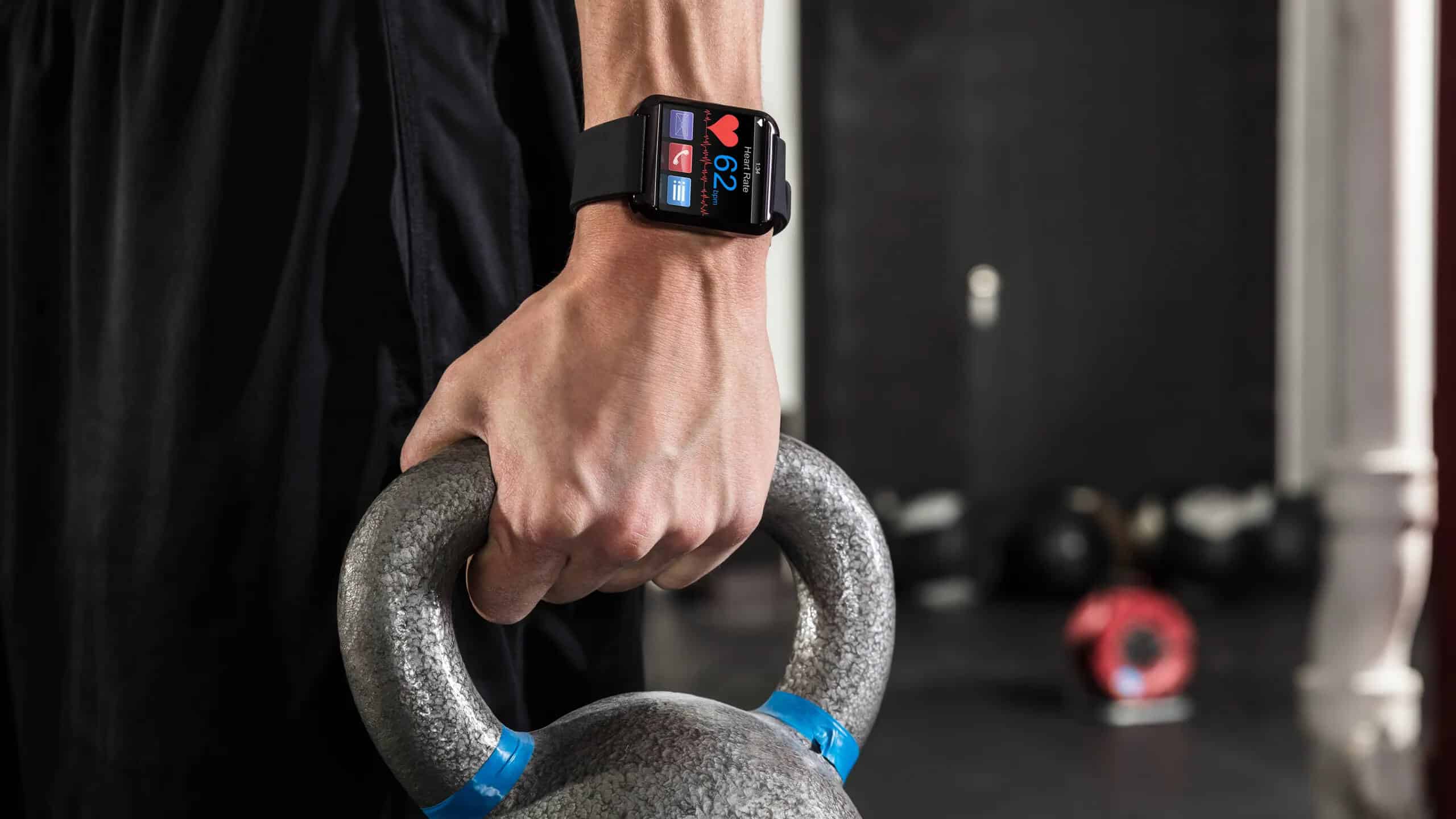 Alt text (in Italian):Smartwatch monitora salute durante allenamento con kettlebell in palestra