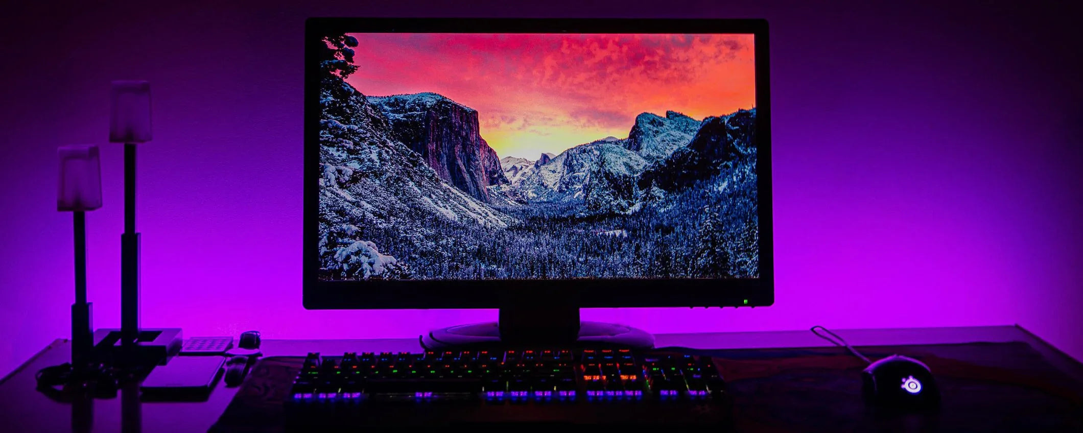 Alt text (in Italian):  
Monitor da gaming con paesaggio montano, illuminazione RGB viola