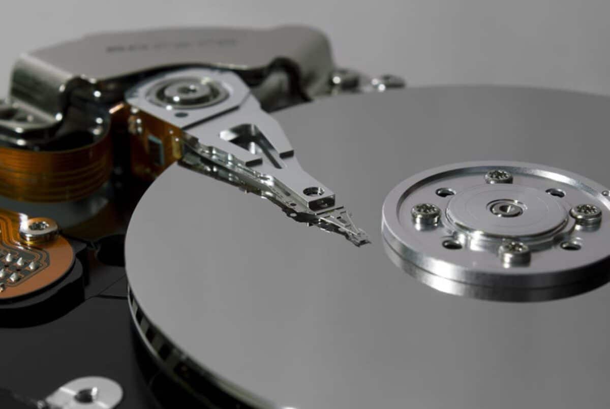 Testo alternativo:Primo piano di un hard disk meccanico con piatti e testina di lettura.