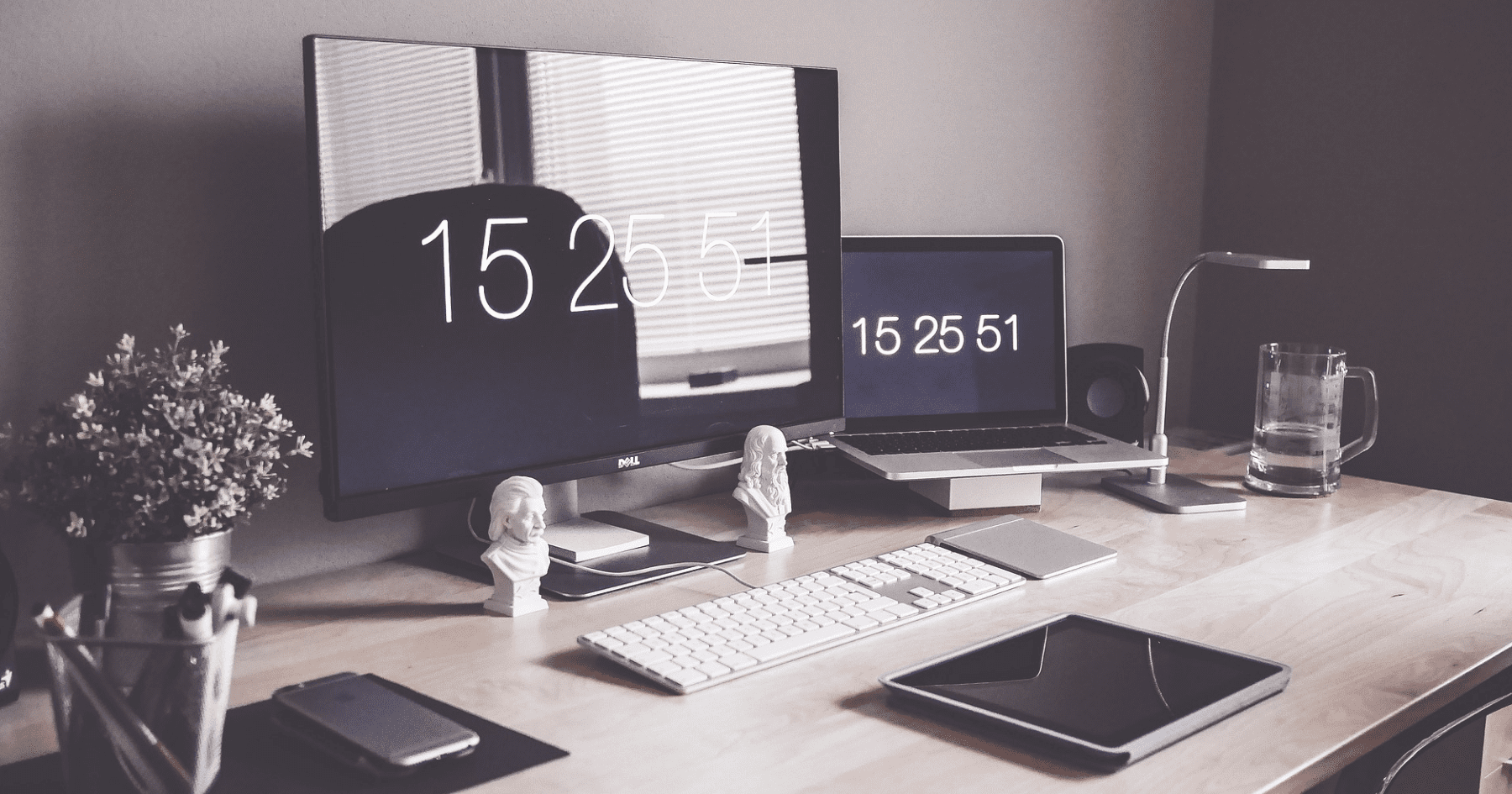 Postazione di lavoro moderna con PC desktop, laptop e tablet su scrivania ordinata.