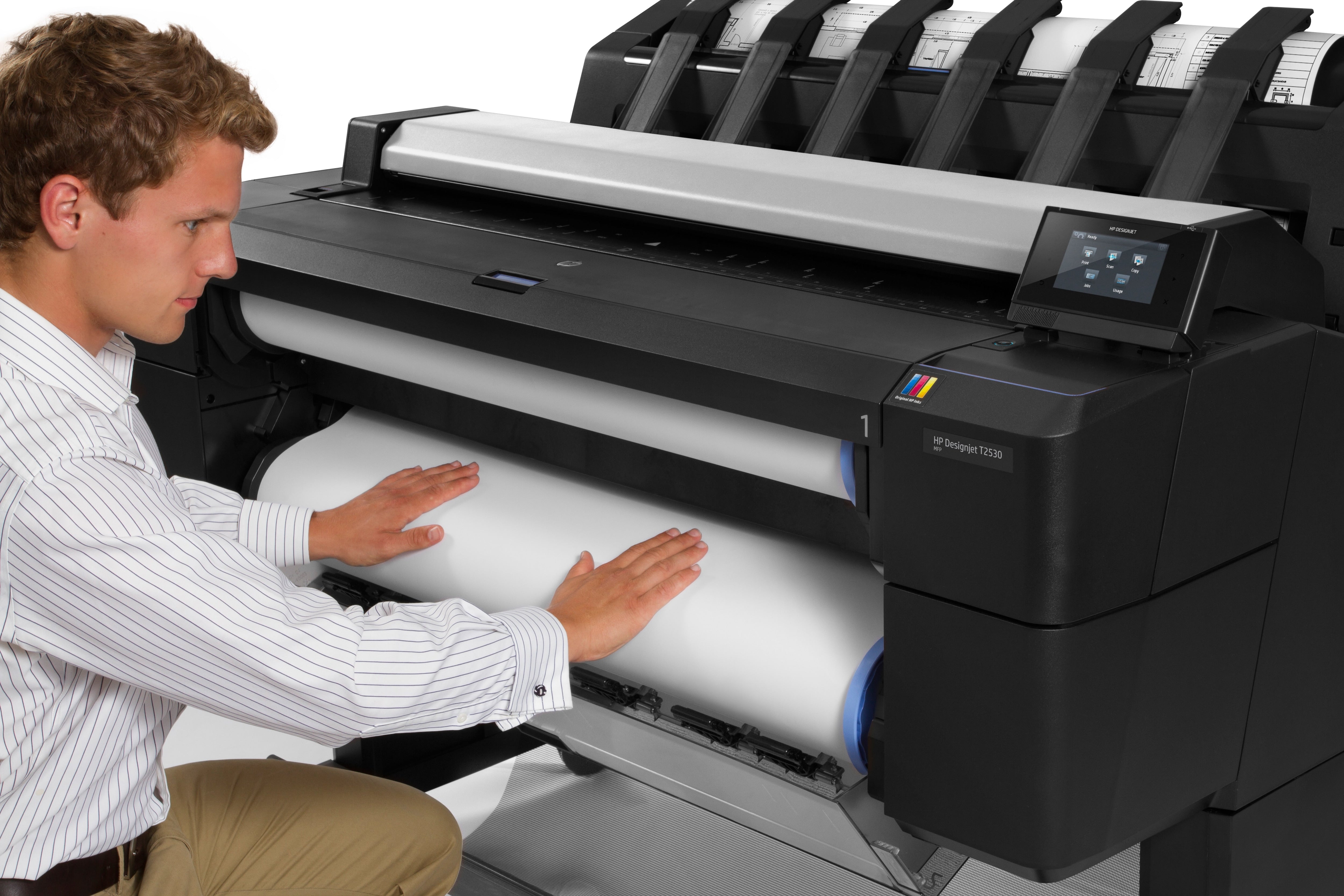 Operatore che carica un nuovo rotolo di carta nel plotter HP DesignJet T2530, ideale per stampe di grande formato.