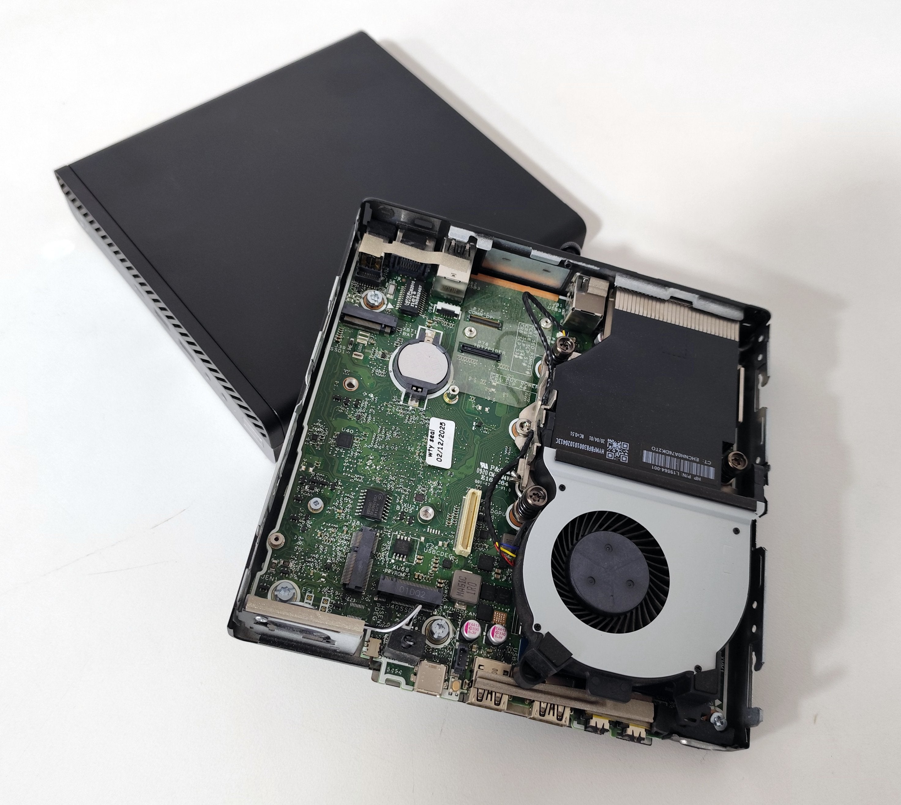 Open mini PC showing internal motherboard and cooling fan on white background, Messoanuovo.it